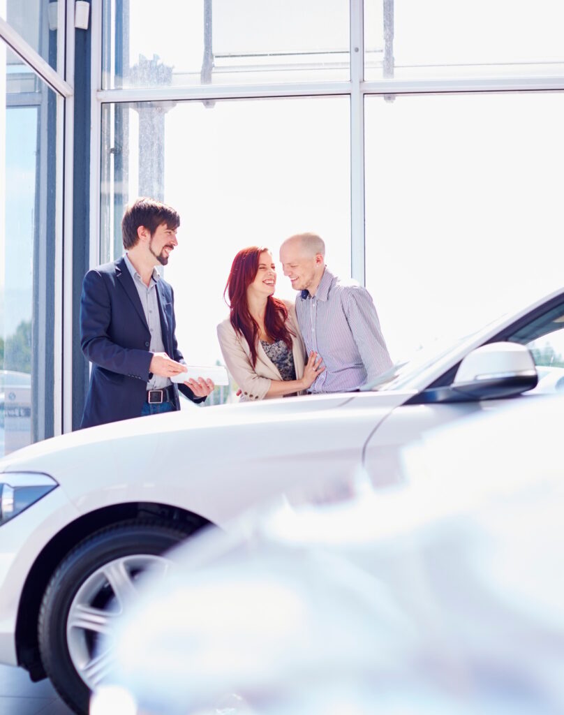 Car dealer with couple in showroom